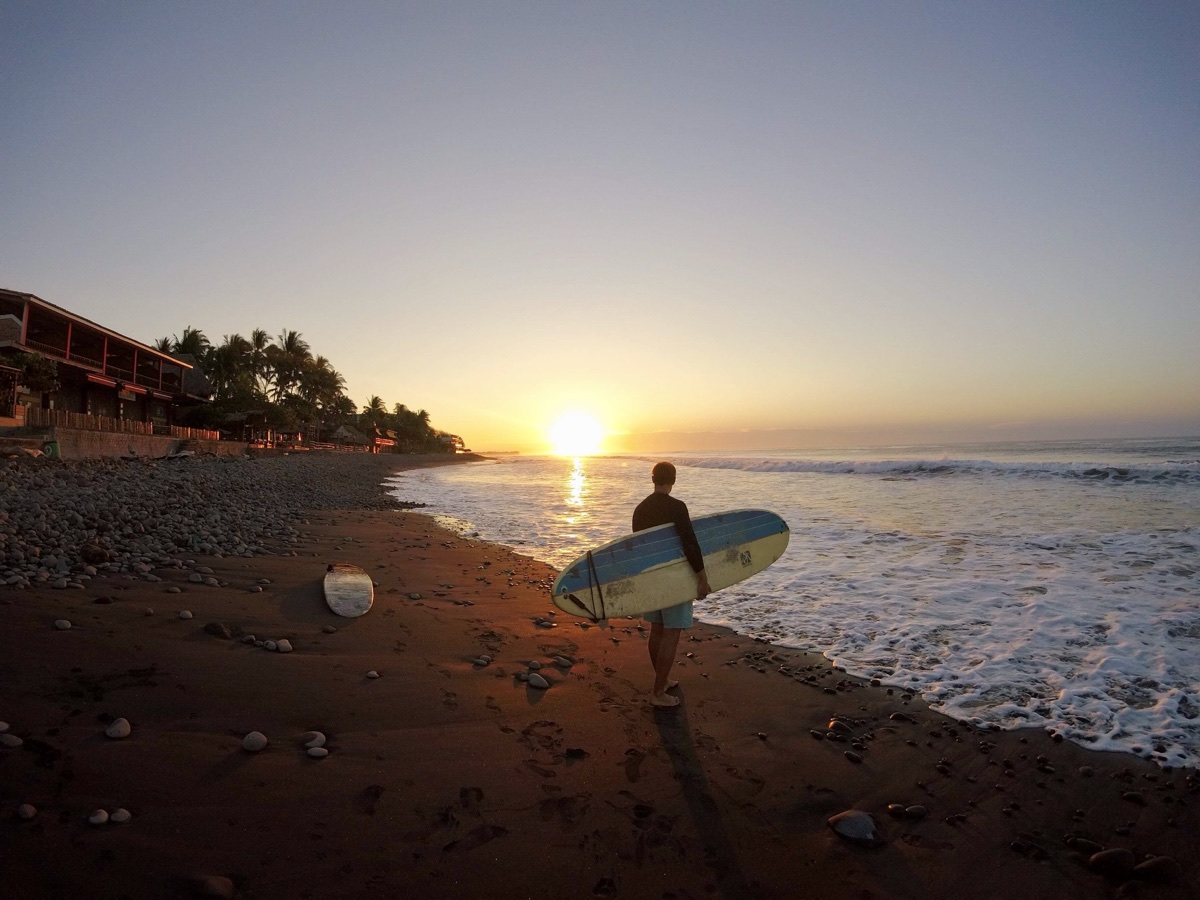 Fabian Frieling am Strand bei Sonnenuntergang mit Surfboard